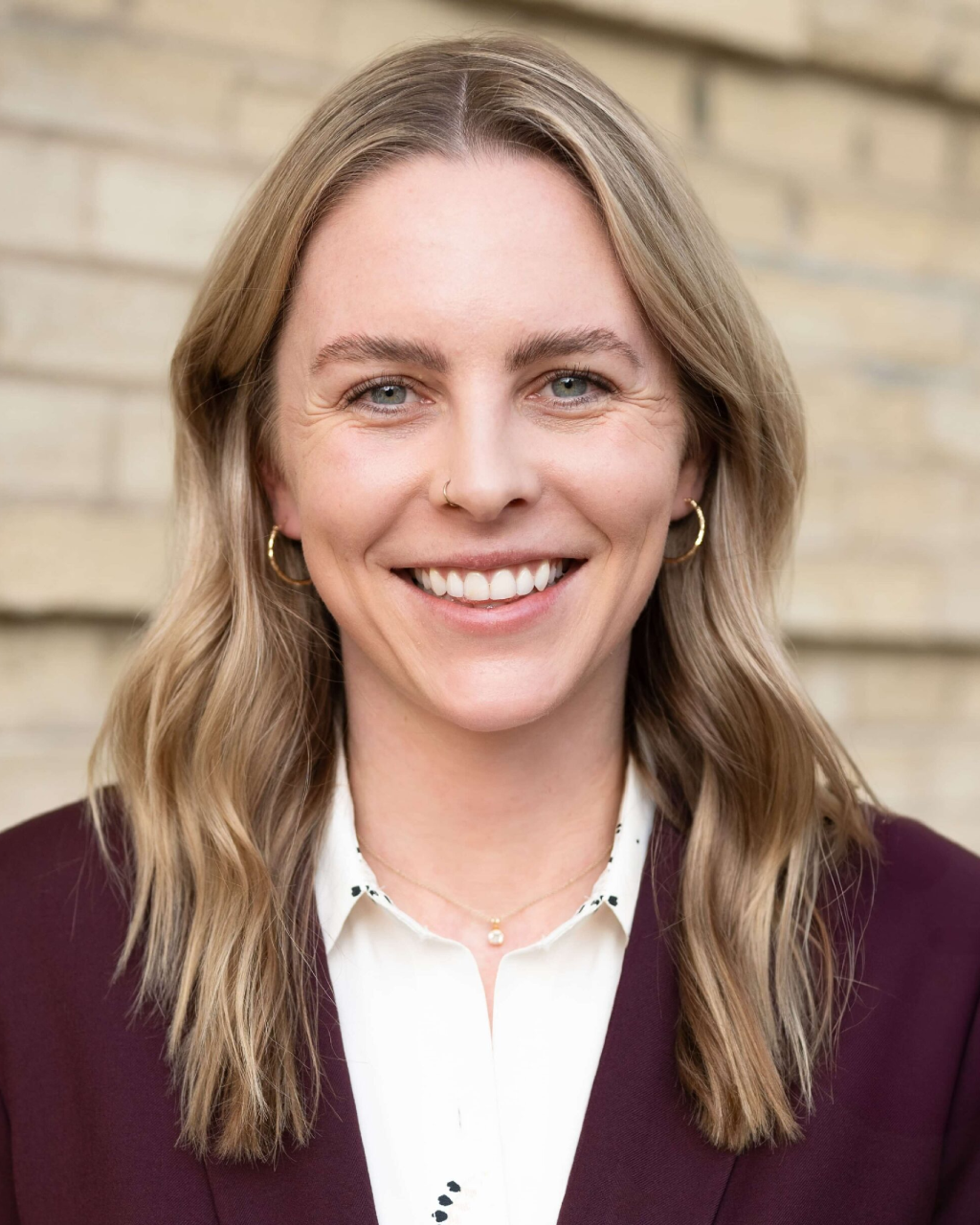 A headshot image of Lauren Greer wearing a maroon jacket and white blouse