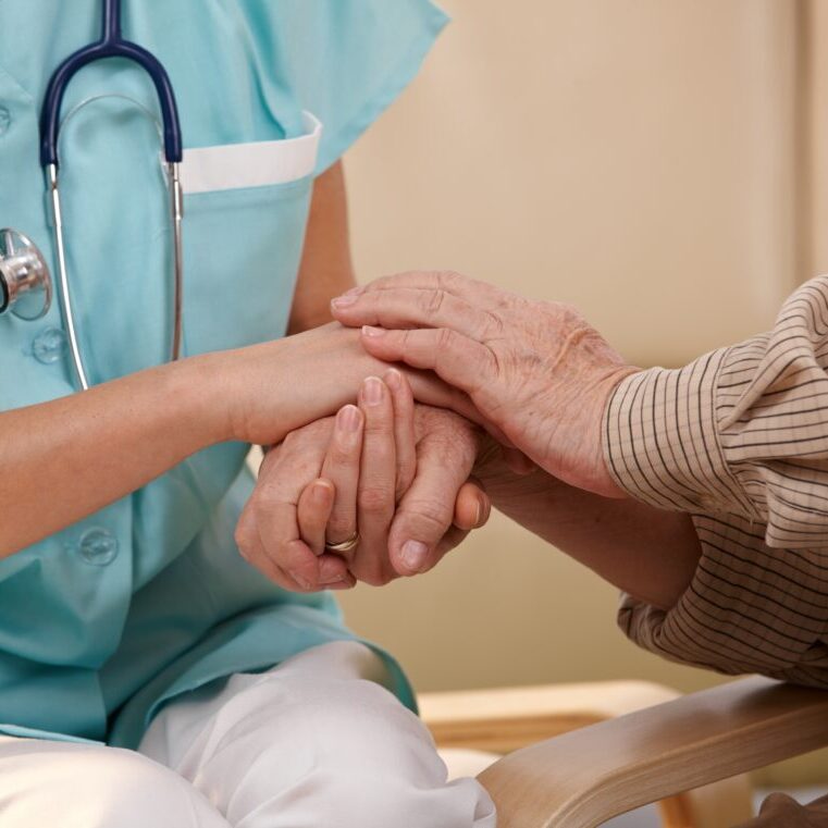 Closeup of joined hands of nurse and elderly patient.