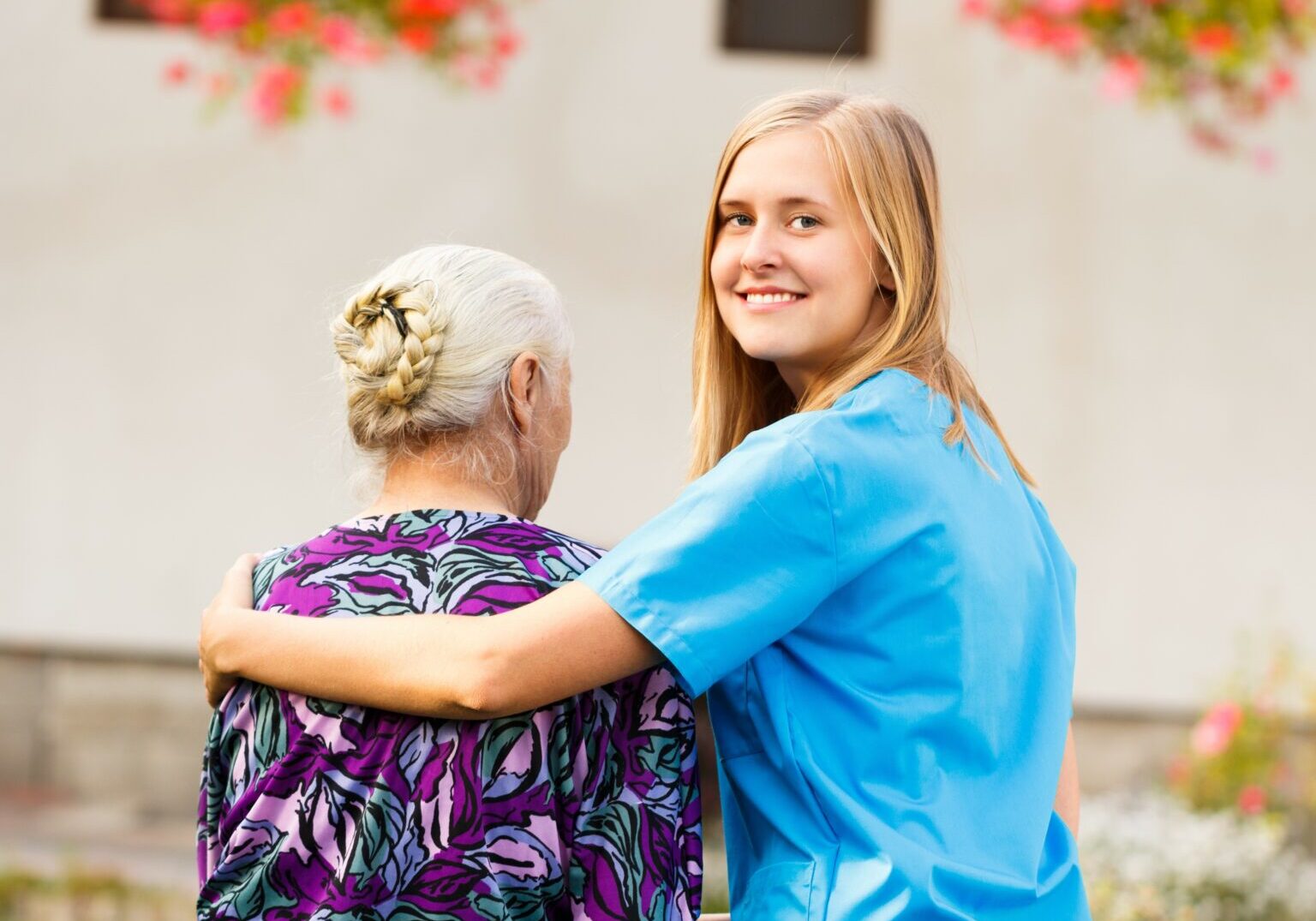 Young kind doctor helping old lady on a walk in the garden.